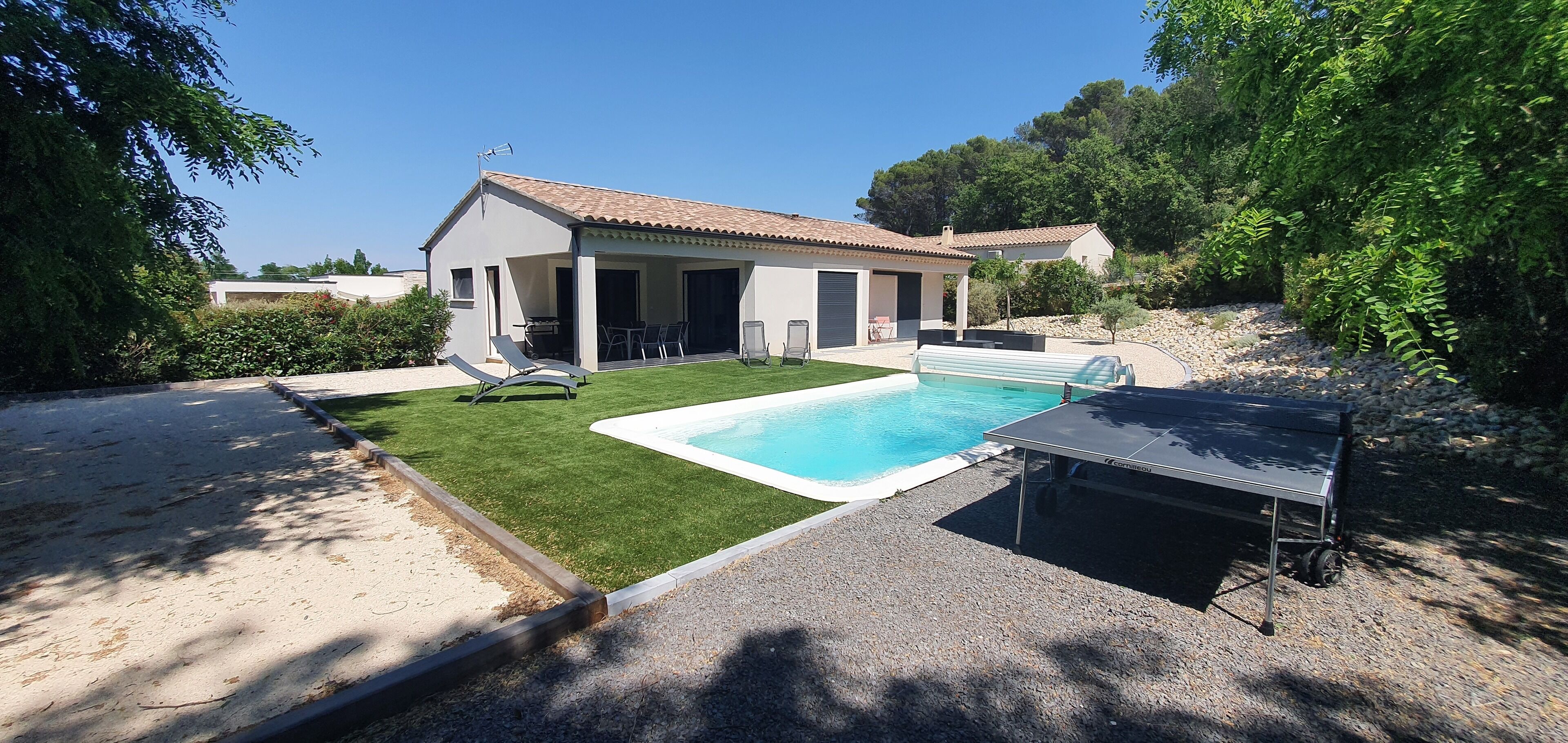 Une maison avec une piscine, un patio couvert et une allée gravillonnée.