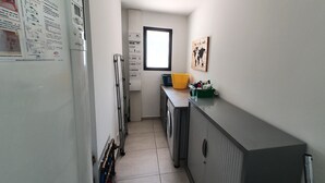 A narrow kitchen with a refrigerator, washing machine, and a window with a world map. - La Villa Beau Soleil (Saint-Julien-de-Peyrolas)