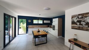 A modern kitchen with a dining area, large windows, and a motivational wall art piece. - La Villa Beau Soleil (Saint-Julien-de-Peyrolas)