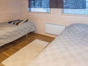 A room with two beds, a radiator, and a window with blinds.