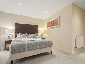 Una camera da letto moderna con un letto grande, lampade ai comodini, un termosifone e un'opera d'arte incorniciata appesa al muro.