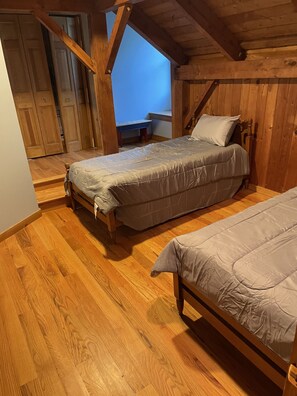Cozy bedroom with two single beds, wooden bench, and small table.