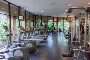 Un gimnasio con cintas de correr, elípticas y equipo de pesas.