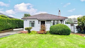 Een gelijkvloers huis met pannendak, een veranda en een verzorgd gazon.