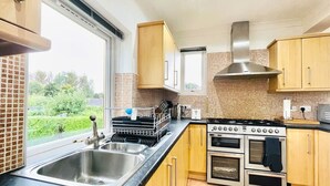 Een moderne keuken met een dubbele spoelbak, roestvrijstalen apparatuur en houten keukenkastjes.