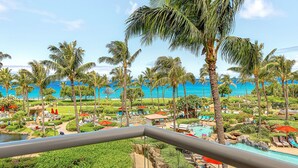 A resort with a pool, palm trees, and a view of the ocean.