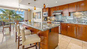 A modern kitchen with wooden cabinets, a granite countertop, and a central island with bar stools.