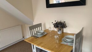 A dining area with a wooden table, four chairs, and a vase with flowers. - Ludlow Cozy Apartment Retreat (Ludlow)