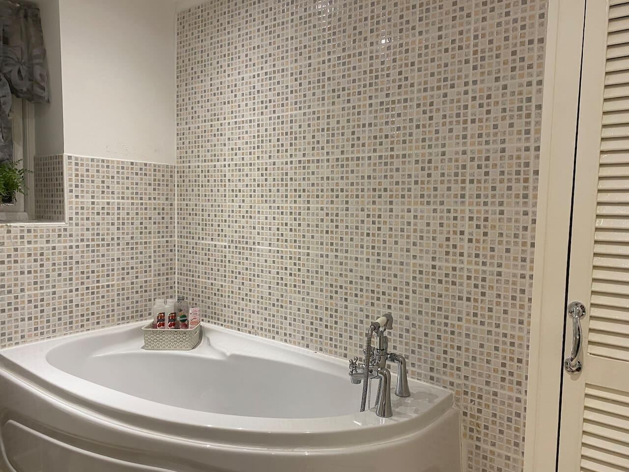 A bathroom with a freestanding bathtub, tiled walls, and a small window.