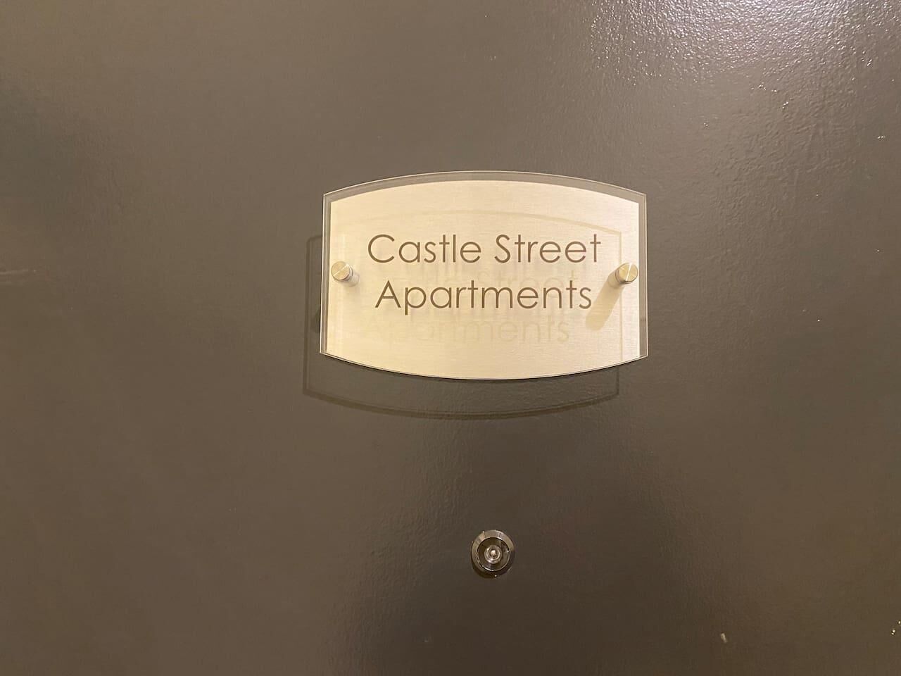 Placa numa porta com a inscrição 'Castle Street Apartments'.