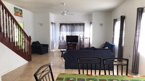A living room with a sofa, TV, and a dining area with chairs and a table. - Apt - Sleeps 5 - Garden - Parking - Balcony (Trelawny)