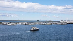 A marina with boats docked, a small boat in the water, and a row of white buildings with a flat roof. - Holiday Apartment "Reeders Topp by Seeblick Ferien" with Harbour View (OstseeResort Olpenitz)