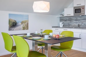 A modern kitchen with a microwave, a kettle, and a wooden backsplash. - Holiday Apartment "Reeders Topp by Seeblick Ferien" with Harbour View (OstseeResort Olpenitz)