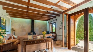 A cozy living area with a wooden ceiling, a fireplace, and a dining table with pottery. - Es Rafalet by Interhome (Llucmajor)