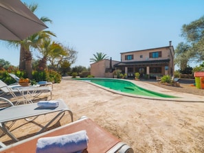 Une piscine entourée de chaises longues, avec une maison en arrière-plan.