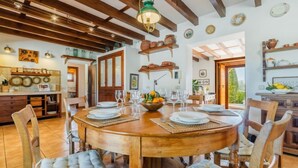 A dining area with a wooden table set for six, surrounded by upholstered chairs. - Es Rafalet by Interhome (Llucmajor)