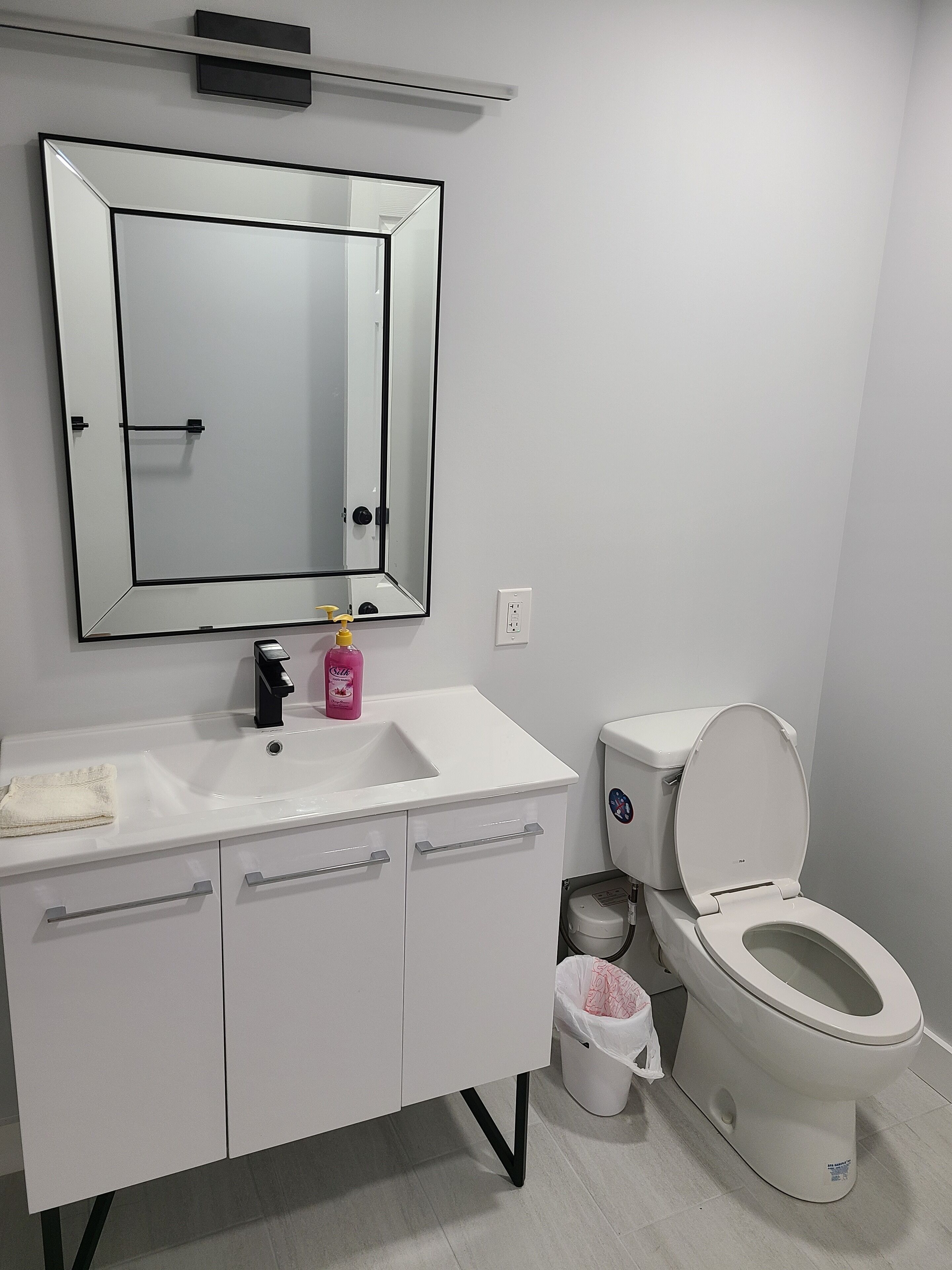 Ein modernes Badezimmer mit Waschbecken, Spiegel und Toilette.