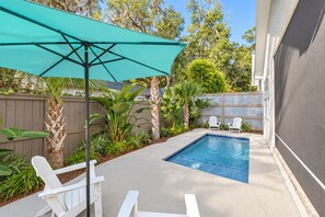 A backyard with a swimming pool, surrounded by plants and a wooden fence.