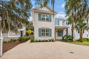 A two-story house with a gravel driveway, green shutters, and a well-maintained lawn.