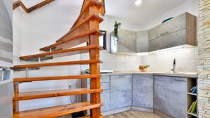 A modern kitchen with grey cabinets, a wooden staircase, and a stone accent wall. - Jungle House With Pool and Hot Tub, Sveti Ivan Zelina, Croatia (Sveti Ivan Zelina)
