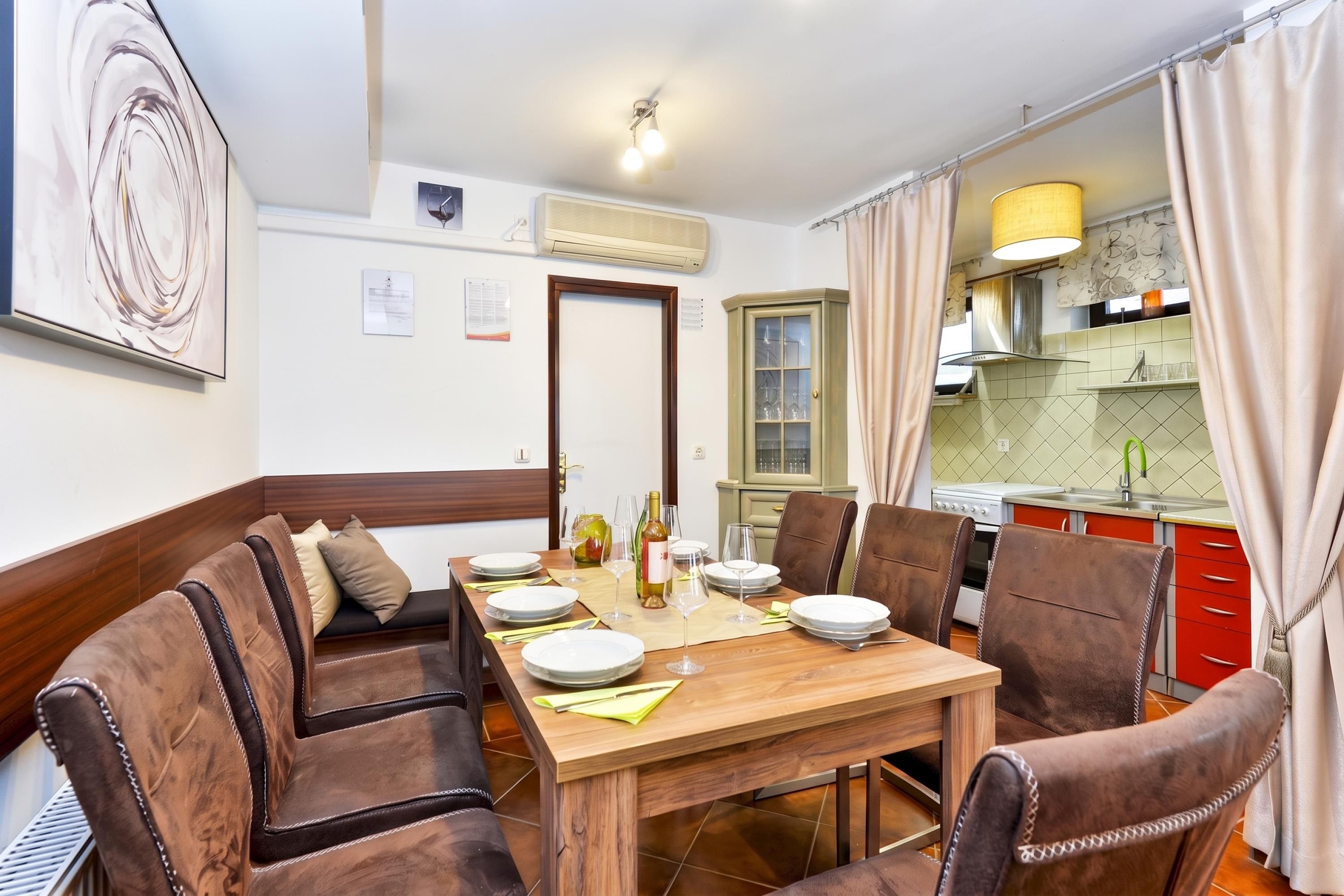 A dining area with a wooden table set for four, surrounded by leather chairs.