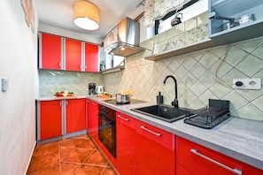 A compact kitchen with red cabinets, a black sink, and a tiled backsplash. - Twin Oasis Retreat with Pool & Spa, Sveti Ivan Zelina, Croatia (Sveti Ivan Zelina)