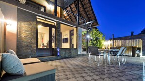 Un patio exterior moderno con suelo a cuadros, una zona de estar con cojines y un comedor.