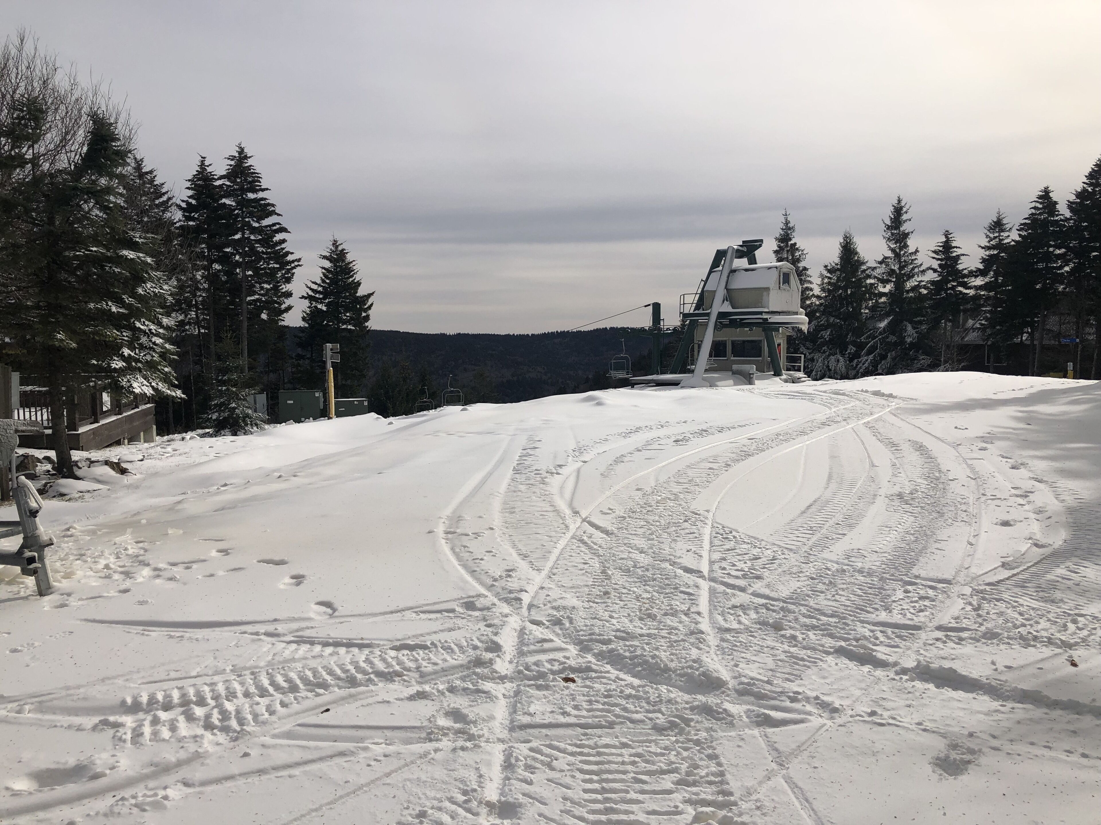 A snow-covered ski slope with ski lifts and trees.