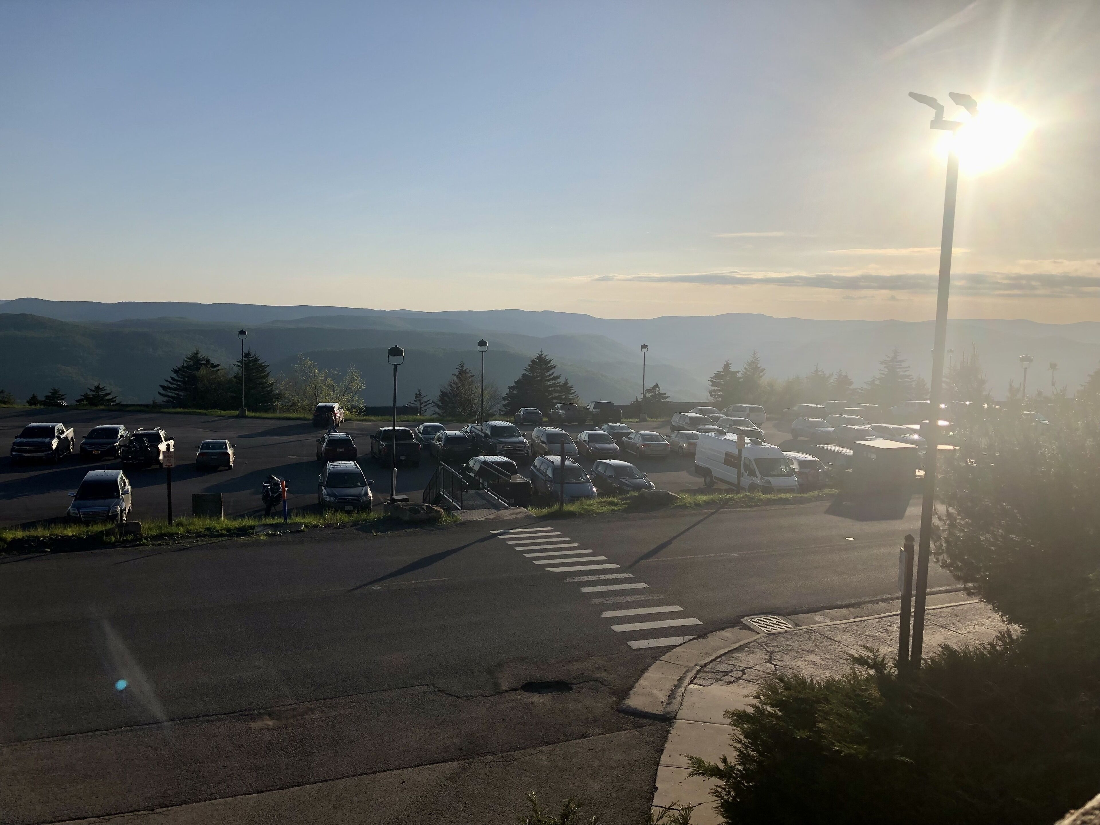 Un parking avec des véhicules et une vue dégagée sur les montagnes lointaines.