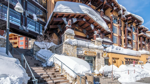 A multi-story hotel with a stone facade, wooden balconies, and a staircase leading to the entrance.