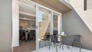 A modern outdoor patio with a glass door leading to a dining area.