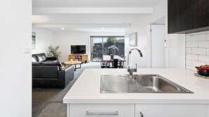 A modern kitchen with a central island, a dining area with a table and chairs, and a living room with a sofa and a TV.