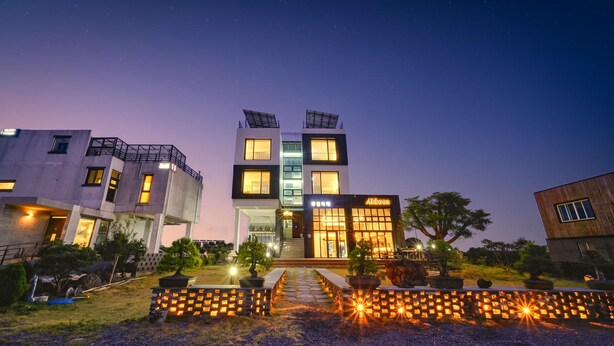 Ein modernes Hotel mit zentralem Eingang, mehreren Etagen und einer gut beleuchteten Fassade.