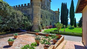 Une cour intérieure agrémentée d’un bâtiment historique, de plantes en pot et d’une pelouse bien entretenue.