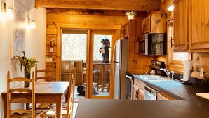 Un interior de madera con cocina, que incluye una mesa de comedor y sillas, un refrigerador y un microondas.
