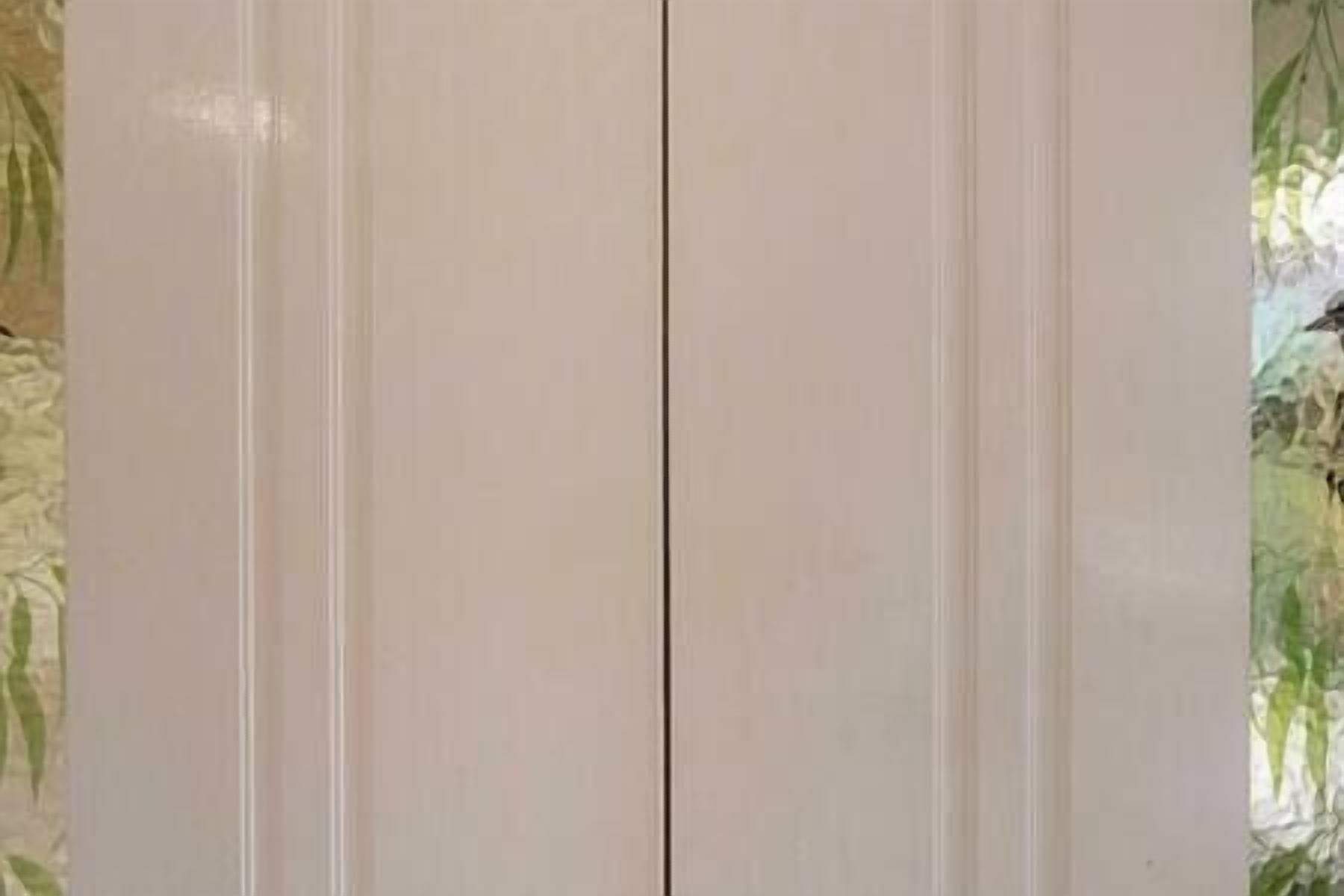 A plain, light-colored door with vertical paneling.