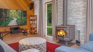 A cozy living room with a fireplace, a bookshelf, and a painting of a forest.