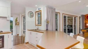 A modern kitchen with a central island, white cabinetry, and a view to the dining area.