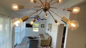 Una sala de estar moderna con una araña en el centro, un sofá, una mesa de centro y una televisión.