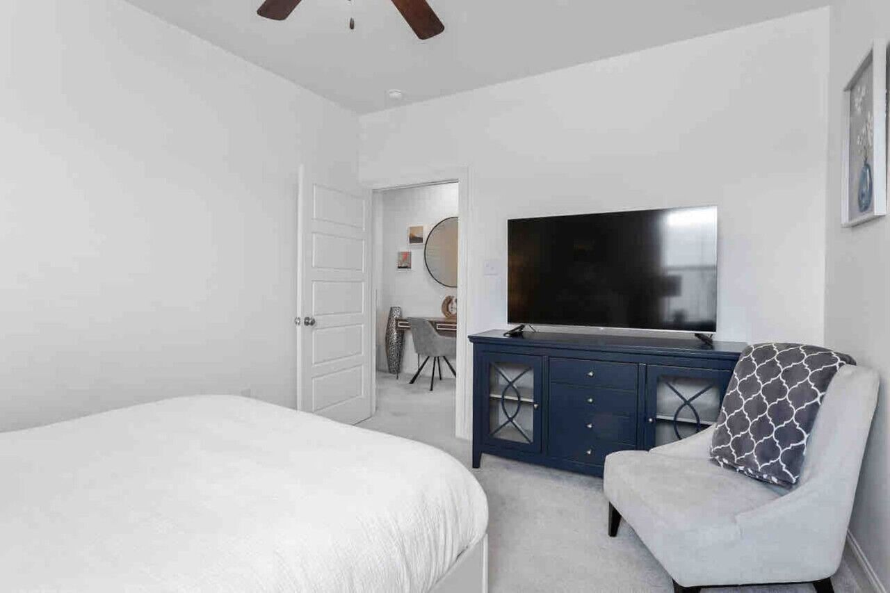 Une chambre à coucher avec un lit, une télévision, une commode et une chaise.