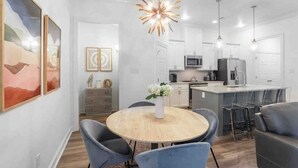 A modern kitchen with a central island, bar stools, and pendant lighting. - Cozy & Stylish 3BD near LSU (Baton Rouge)