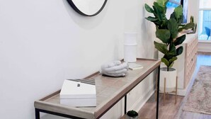 A hallway with a long, minimalist console table, a large mirror, and a potted plant. - Cozy & Stylish 3BD near LSU (Baton Rouge)