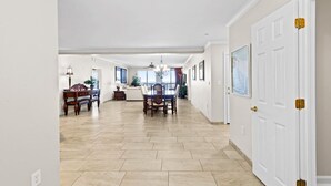 A spacious hallway with a dining area, a sofa, and a chandelier.