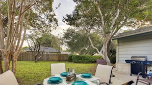 An outdoor patio with a round table set for four, surrounded by chairs, and a barbecue grill in the background. - San Antonio Home: Near Nature, Parks & Trails (San Antonio)