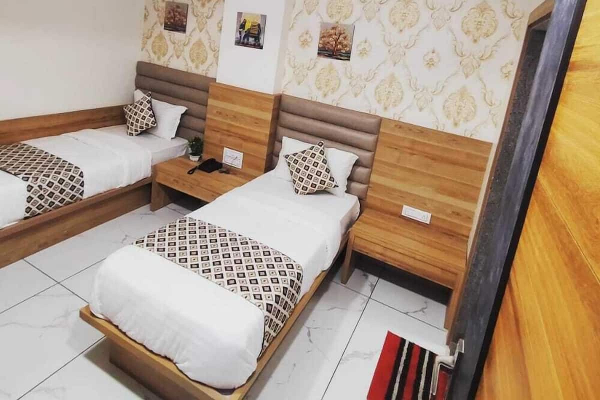 A hotel room with two beds, a ceiling fan, and patterned wallpaper.