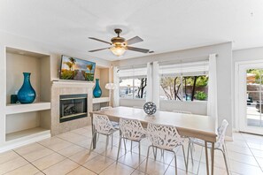 A dining area with a fireplace, a ceiling fan, and a large window with curtains. - Amazing 5 BDR, Resort Style Pool w/Heater and Games. (Henderson)