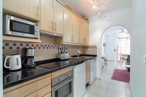 Une cuisine moderne dotée d’appareils électroménagers en acier inoxydable, de meubles en bois et d’un dosseret carrelé.