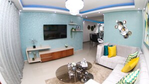 A modern living room with a TV, sofa, coffee table, and decorative items. - ✨ Luxurious 3-Bedroom Apartment with Pool & 24/7 security  (Santiago De Los Caballeros)