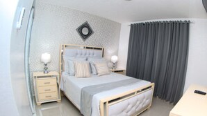 A neatly arranged bedroom with a bed, bedside tables, lamps, and a mirror on the wall. - ✨ Luxurious 3-Bedroom Apartment with Pool & 24/7 security  (Santiago De Los Caballeros)