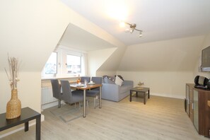 Un salon moderne comprenant un coin repas, un canapé, une petite table et un radiateur.